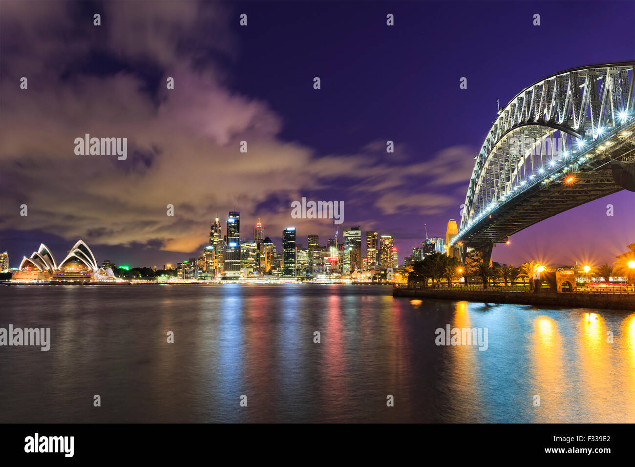 La città di Sydney CBD in Australia come crepuscolo da attraverso il porto con il ponte e grattacieli i punti di riferimento Foto Stock