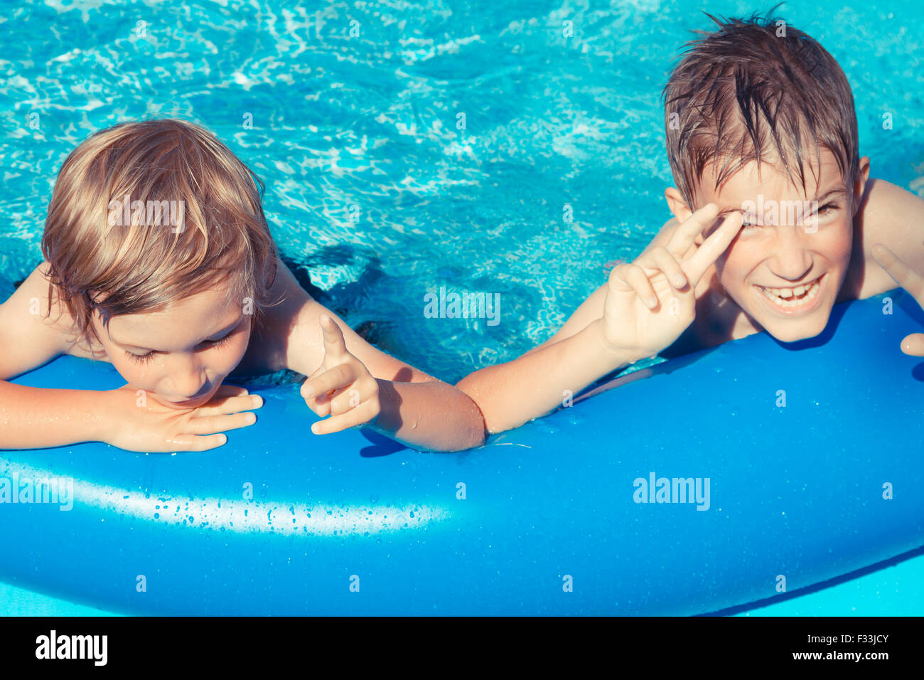 Due giovani ragazzi all'aperto a giocare in piscina gonfiabile. Foto Stock