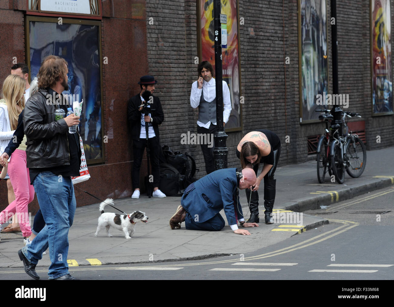 Un uomo umiliato pubblicamente da un dominatrix nelle strade di Soho, dove è stato realizzato a leccare il suo sputo e aveva sigarette stubbed fuori sulla sua linguetta come ha camminato intorno a carponi che indossa un collare doggy su una catena. Dotato di: Uomo pubblicamente hum Foto Stock