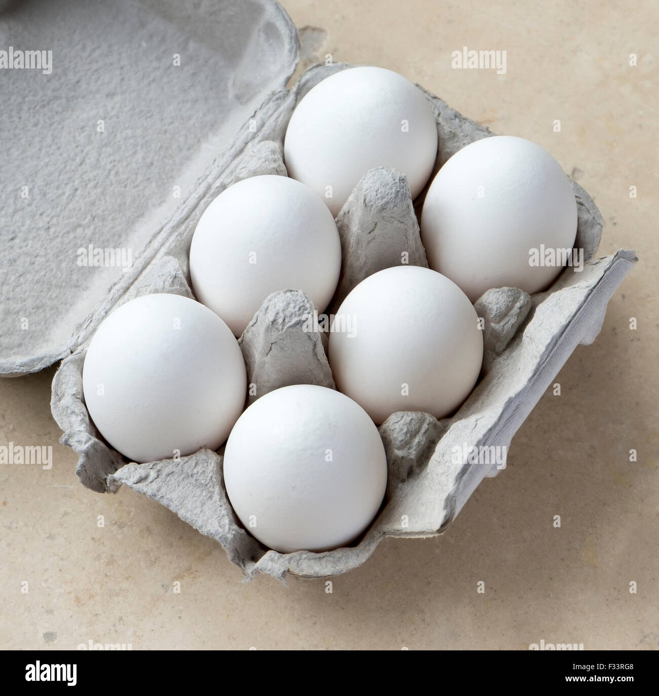 Sei uova di colore bianco in cartone sulla superficie di pietra Foto Stock