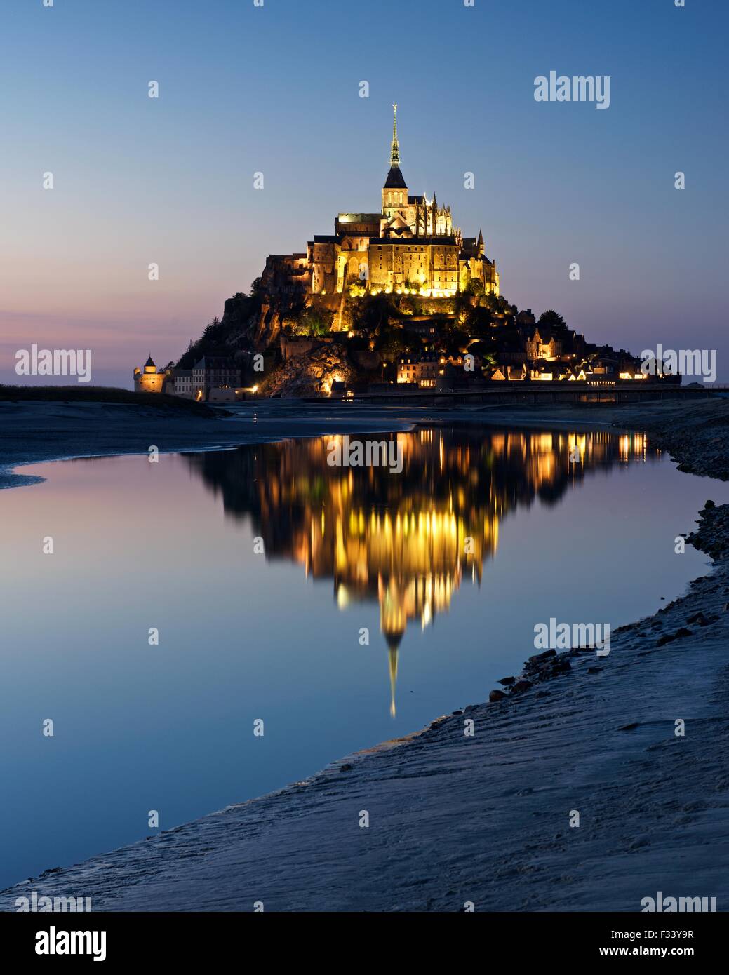 Una immagine a colori di riflessioni di Mont Saint Michel accesa fino al tramonto in una piscina di acqua sulla spiaggia al Mont Saint Michel Foto Stock