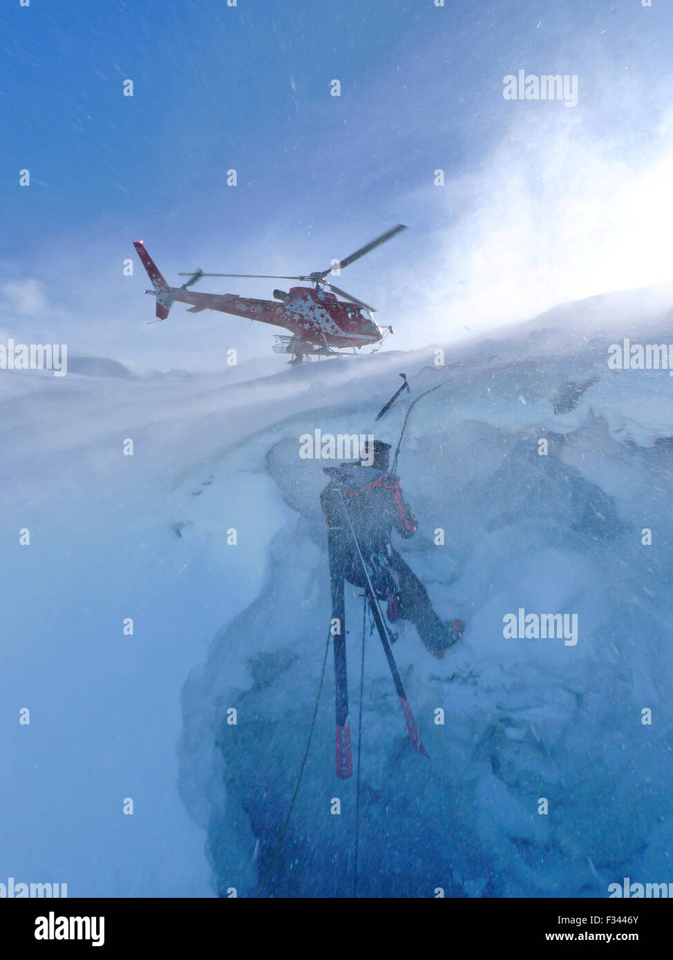 Una montagna tecnico di soccorso è discendente in un crepaccio. Quando un fuori pista sciatore irrompe attraverso la neve e si snoda lungo il ghiacciaio, l unica via di uscita è in corso di winched fino dai soccorritori della Air Zermatt. Questa squadra è una delle più trafficate e professare Foto Stock