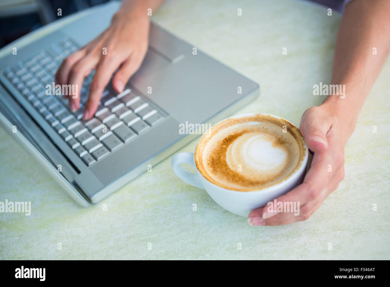 Donna godendo un cappuccino con laptop Foto Stock