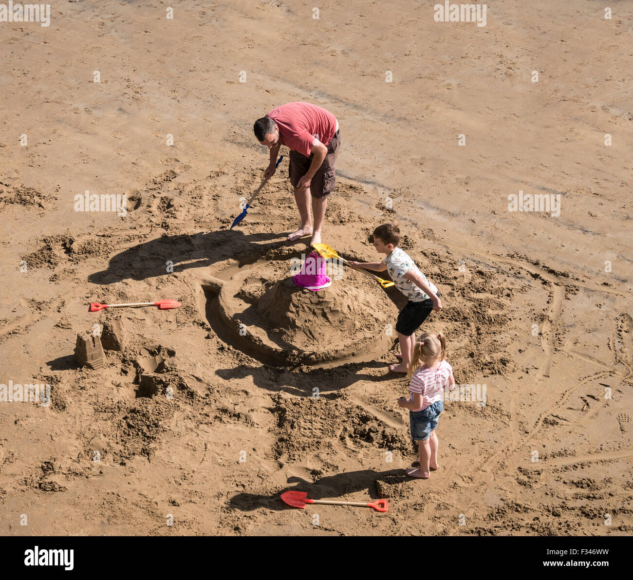Padre e figli costruire castelli di sabbia sulla spiaggia Foto Stock