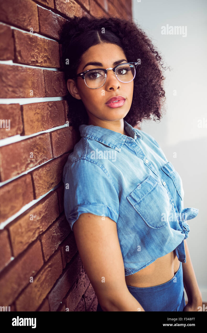 Attraente hipster appoggiata contro rosso Sfondo mattone Foto Stock