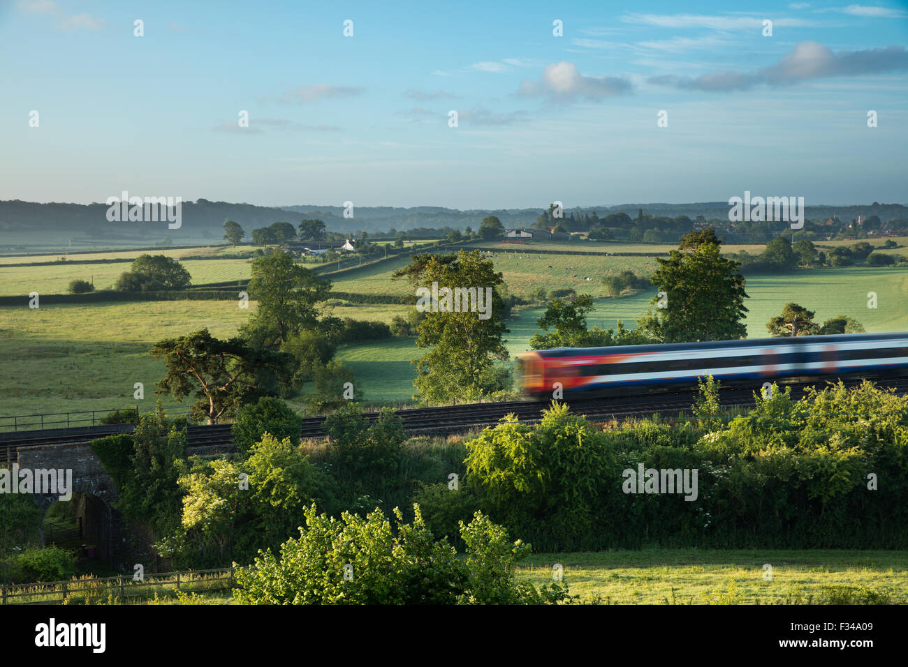 Il London Waterloo a Exeter treno passa Milborne stoppino in una nebbiosa mattina d'estate, Somerset, Inghilterra, Regno Unito Foto Stock
