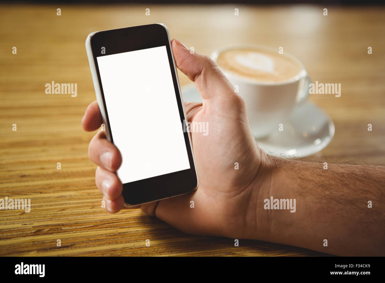 Uomo che utilizza il suo smartphone con caffè Foto Stock