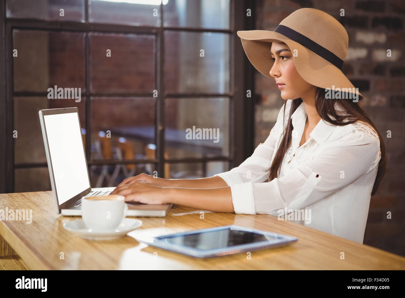 Una imprenditrice usando il suo computer portatile mentre si gusta un caffè Foto Stock