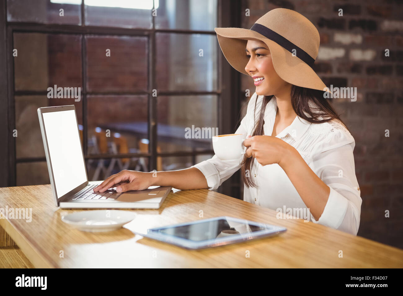 Una imprenditrice usando il suo computer portatile mentre si gusta un caffè Foto Stock