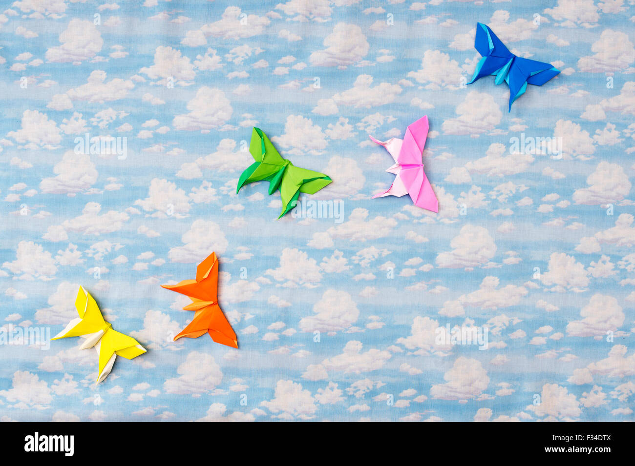 Origami colorate farfalle di carta su un cielo nuvoloso sfondo pattern Foto Stock