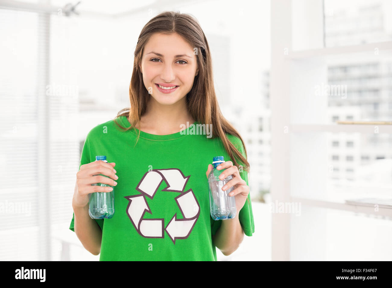 Sorridente eco-minded brunette tenendo il riciclaggio di bottiglie Foto Stock