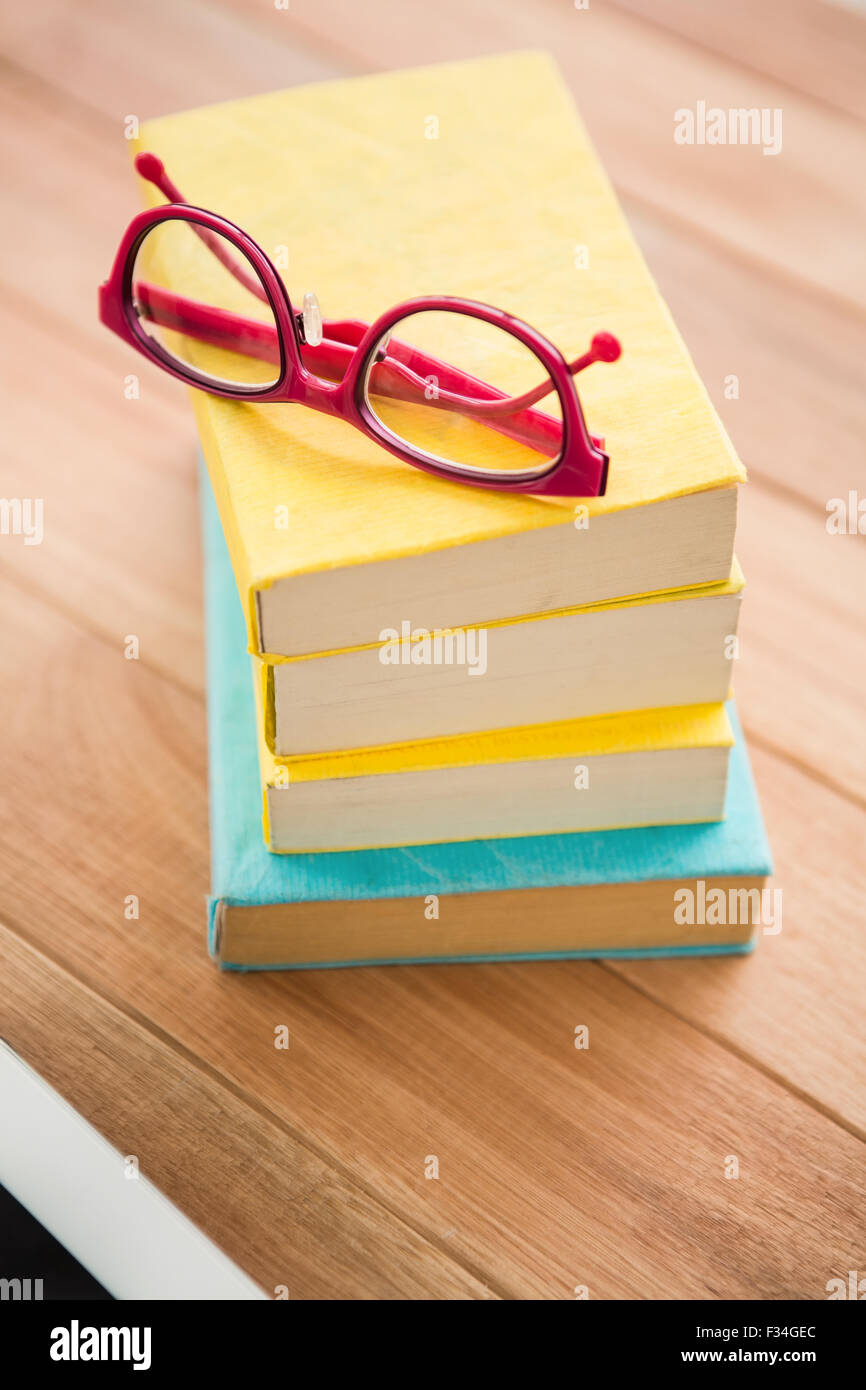 Red gli occhiali da lettura sulla pila di libri Foto Stock