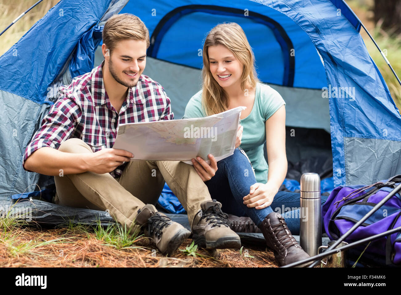Giovani piuttosto escursionista giovane seduto in una tenda guardando alla mappa Foto Stock
