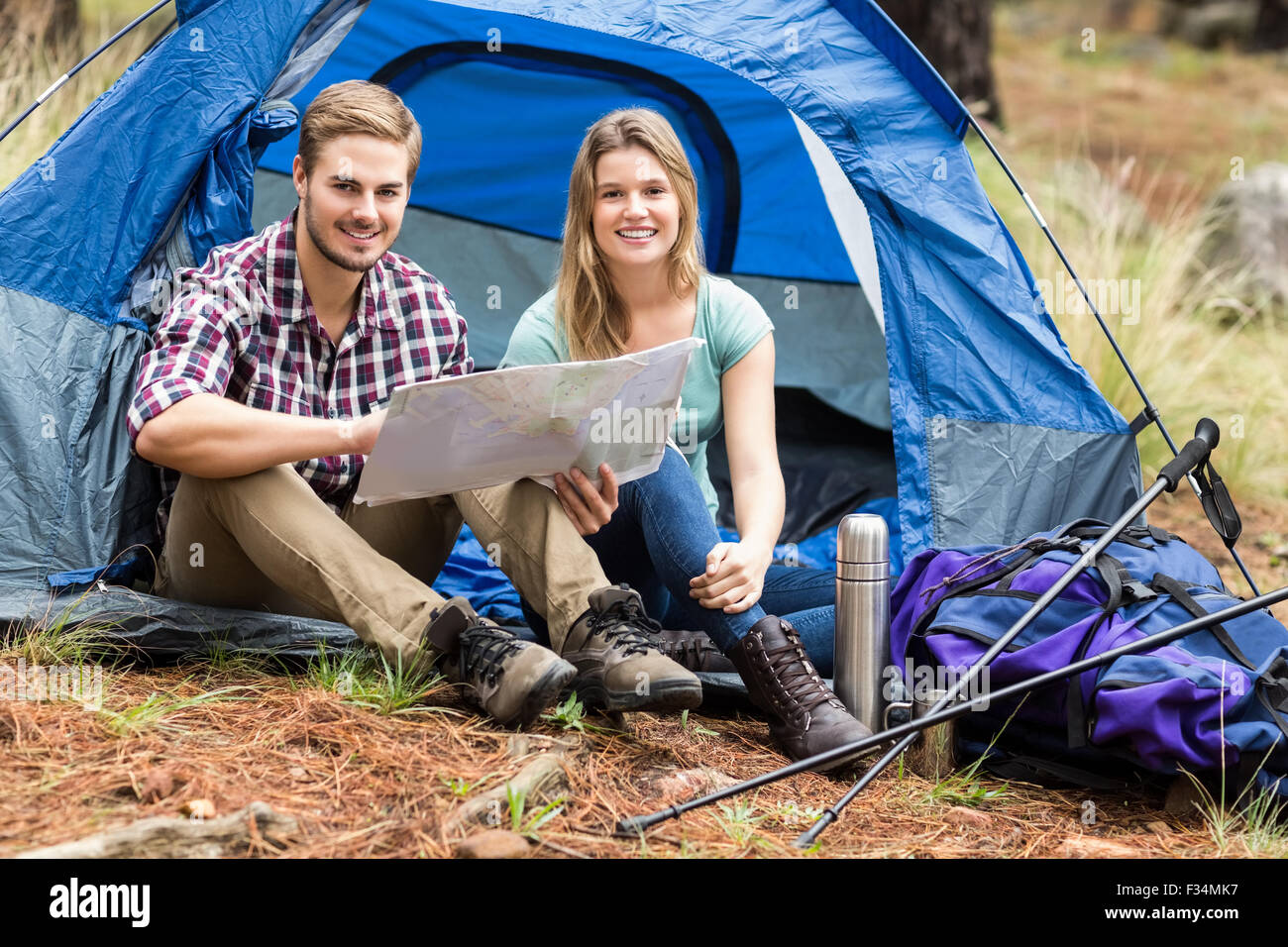 Giovani piuttosto escursionista giovane seduto in una tenda guardando alla mappa Foto Stock