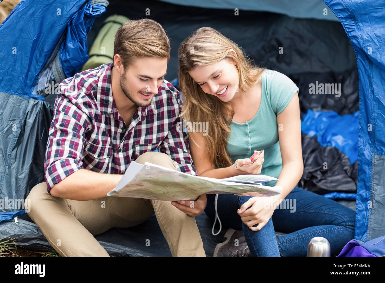 Giovani piuttosto escursionista giovane seduto in una tenda guardando alla mappa Foto Stock