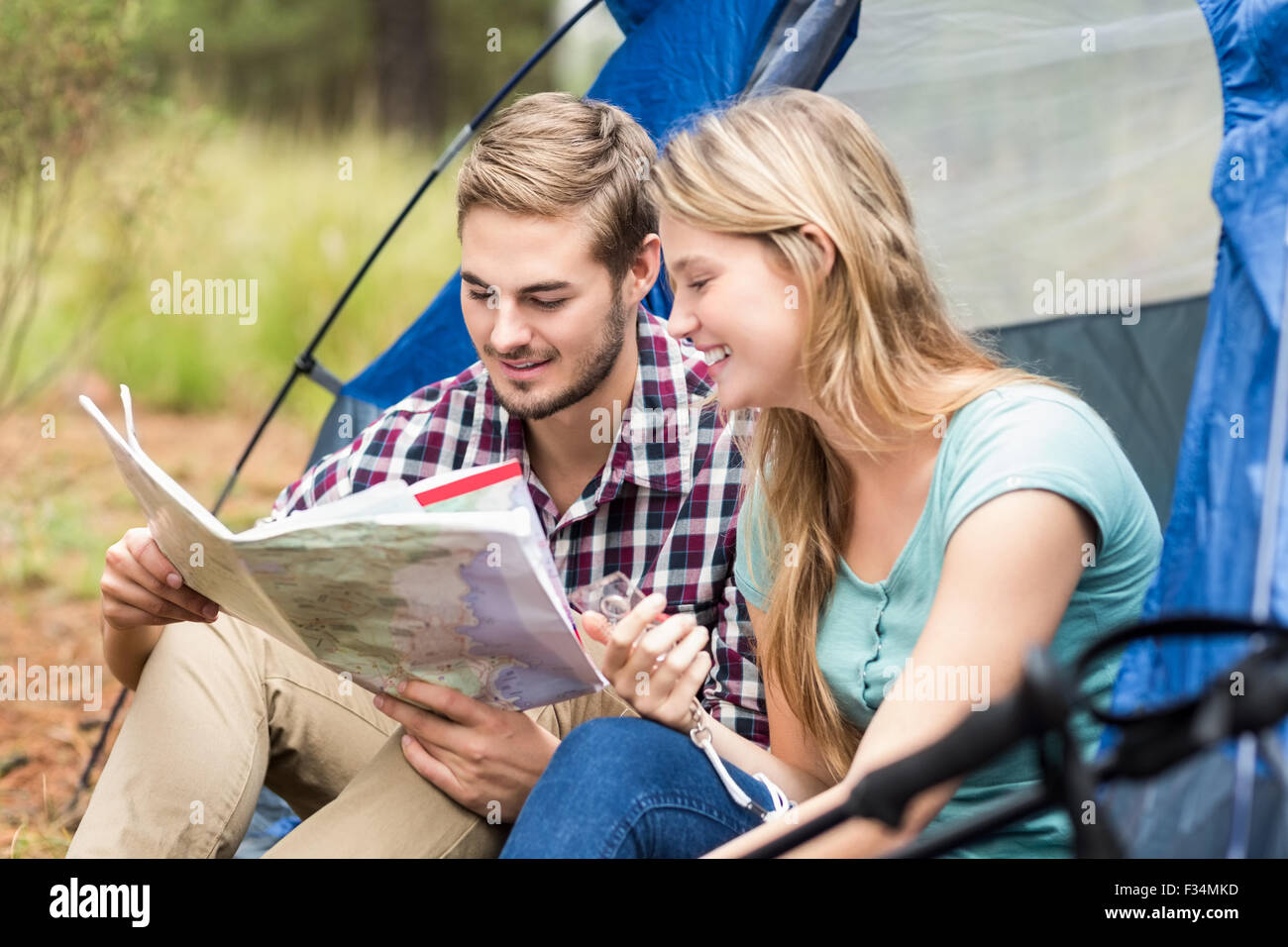Giovani piuttosto escursionista giovane seduto in una tenda guardando alla mappa Foto Stock