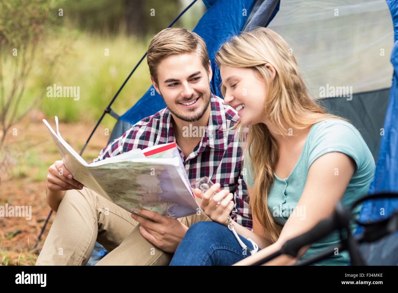 Giovani piuttosto escursionista giovane seduto in una tenda guardando alla mappa Foto Stock