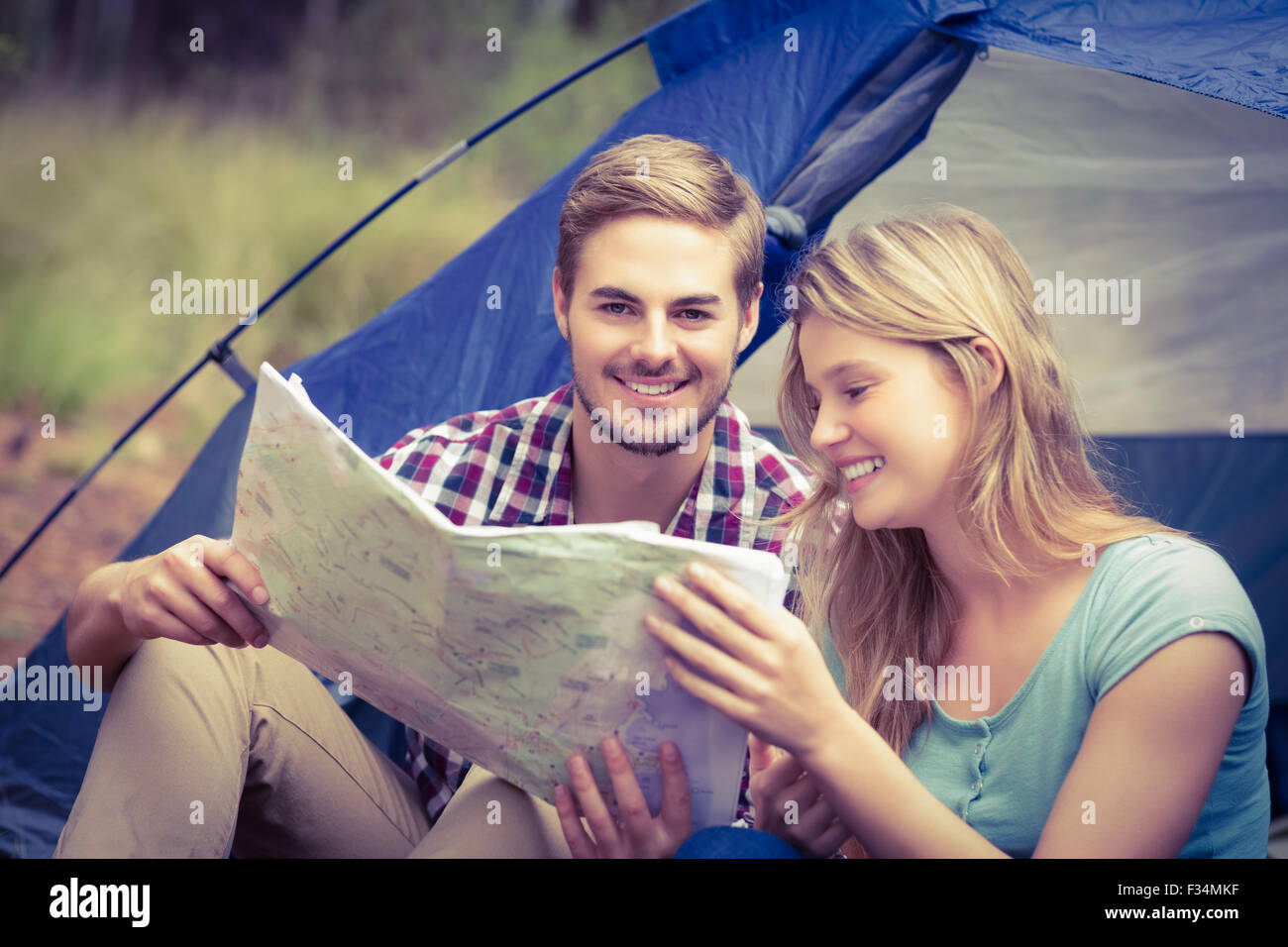 Giovani piuttosto escursionista giovane seduto in una tenda guardando alla mappa Foto Stock