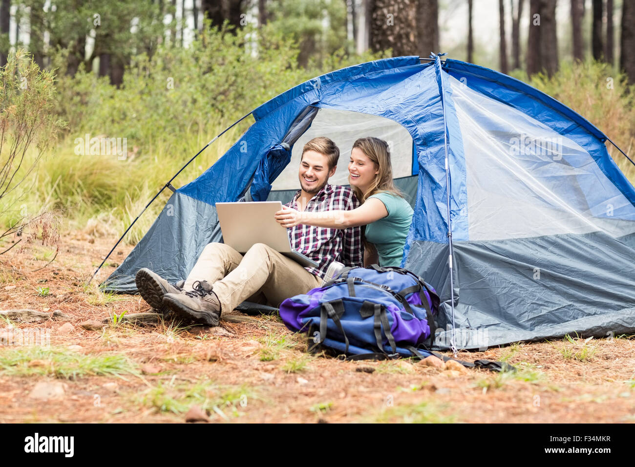 Giovani piuttosto escursionista giovane seduto in una tenda guardando al laptop Foto Stock