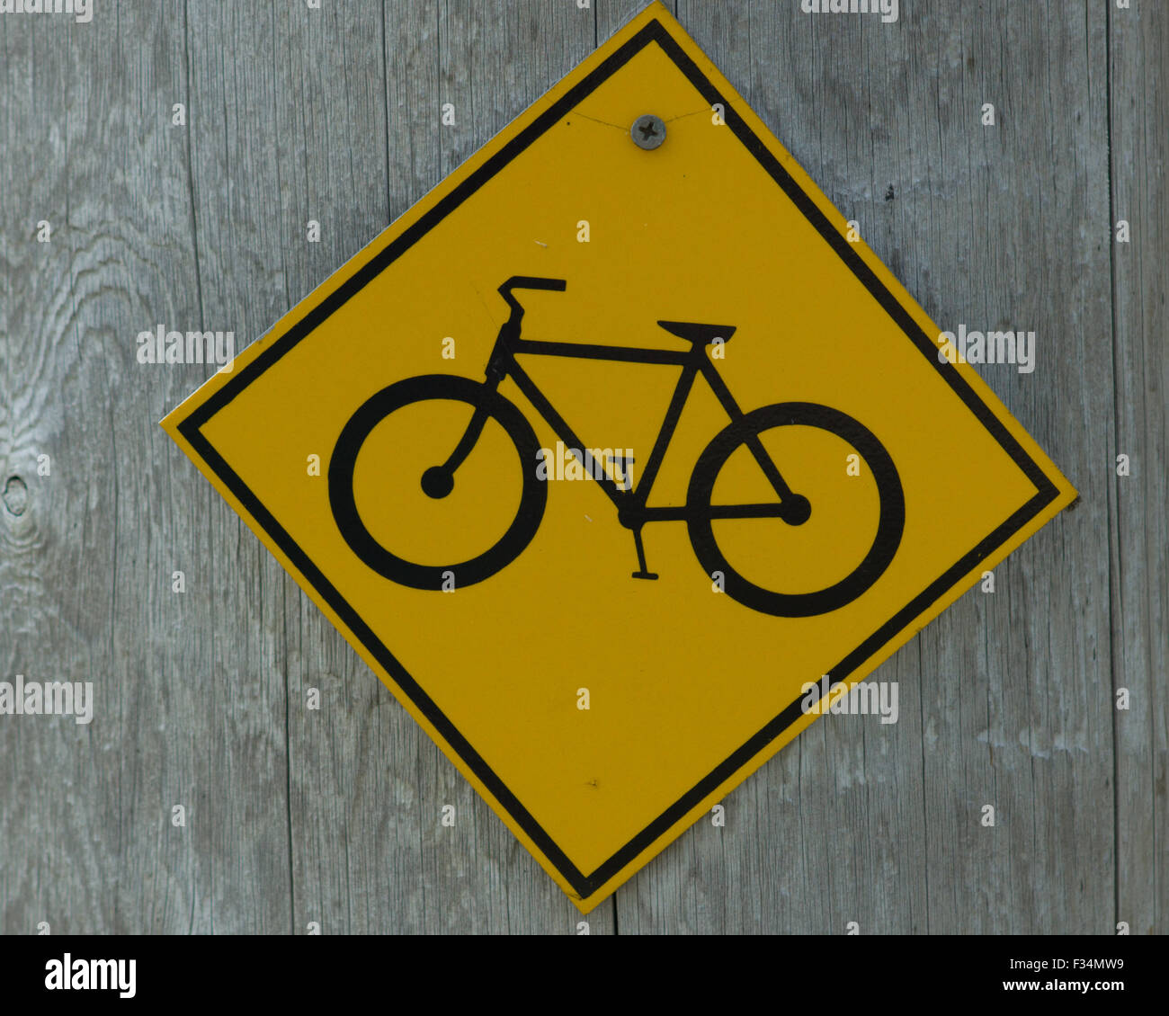 Un giallo, segno di diamante con una bicicletta silhouette su uno sfondo di legno i driver di avvertimento di mountain bike trail. Foto Stock