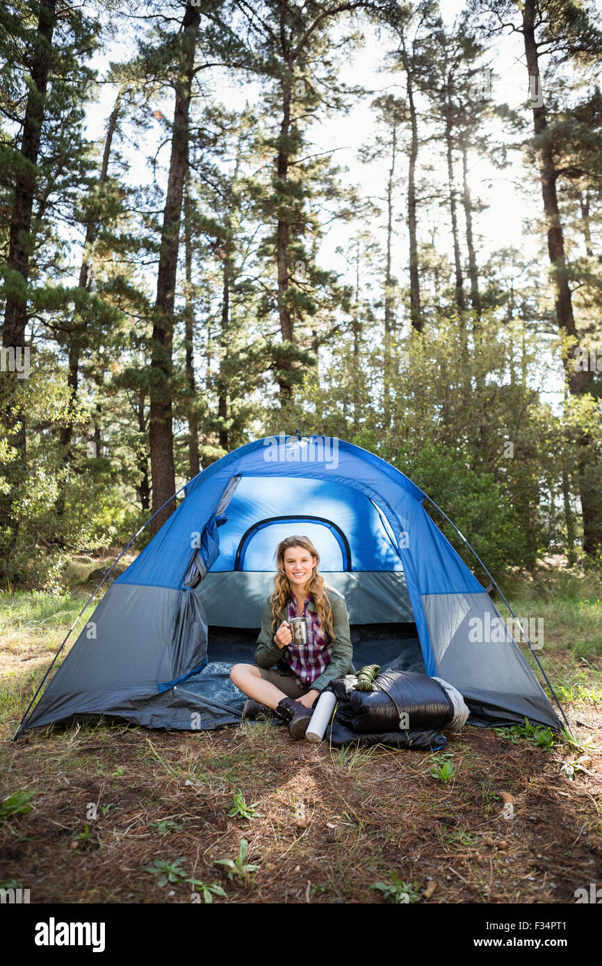 Bella bionda camper sorridente e seduta in tenda Foto Stock