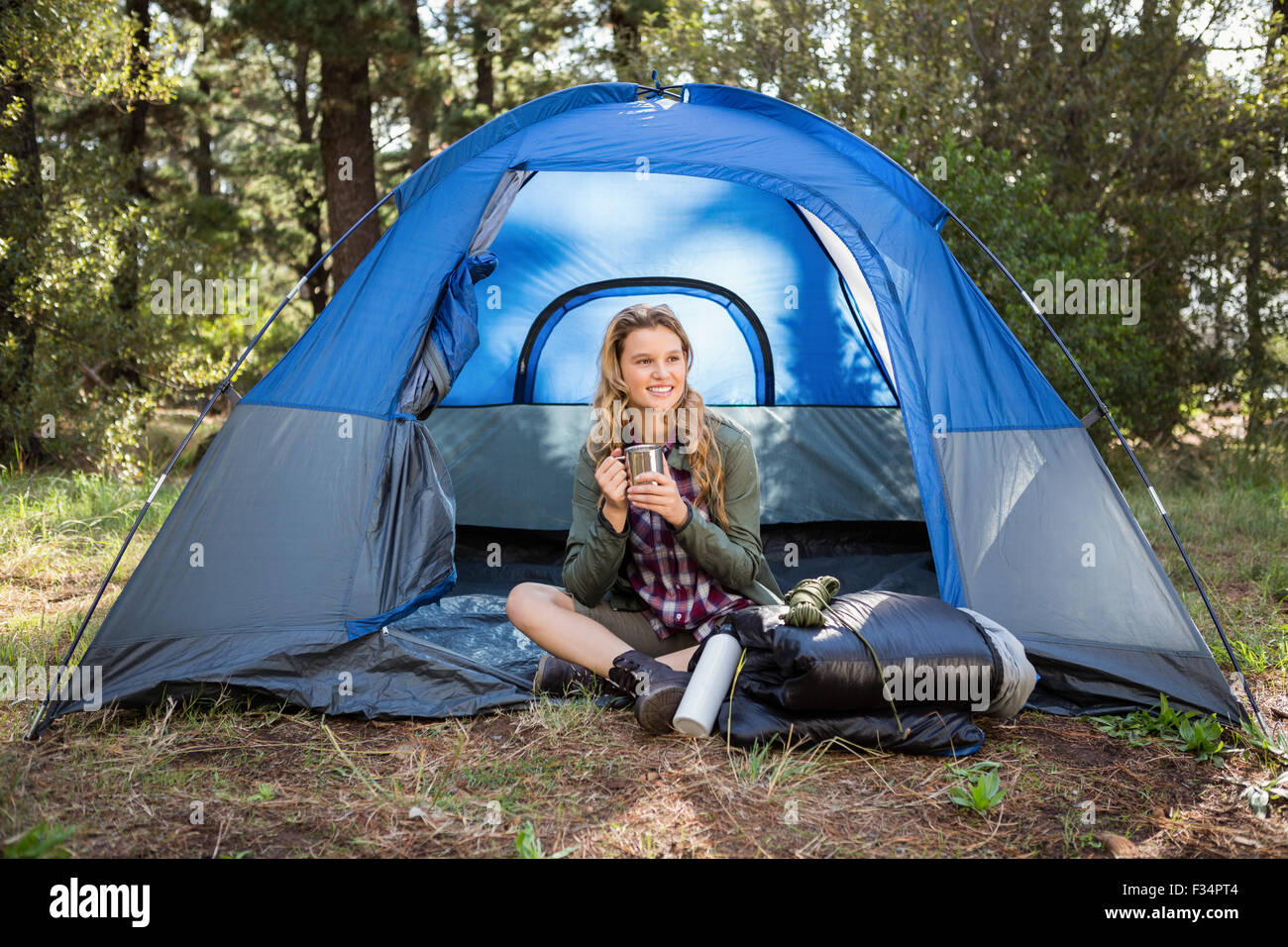 Bella bionda camper sorridente e seduta in tenda Foto Stock