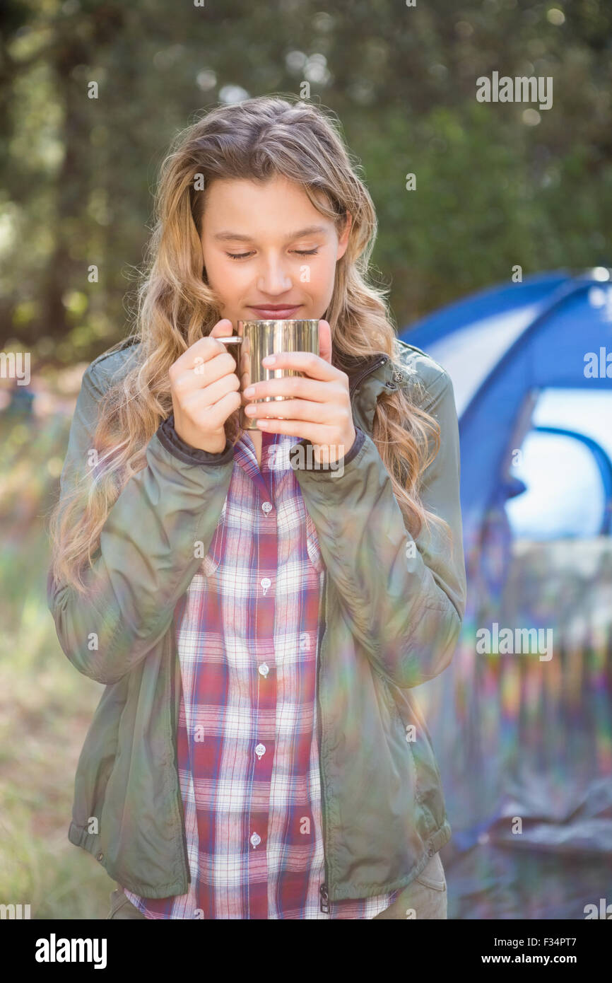 Bella bionda camper godendo di bevanda nella parte anteriore della tenda Foto Stock