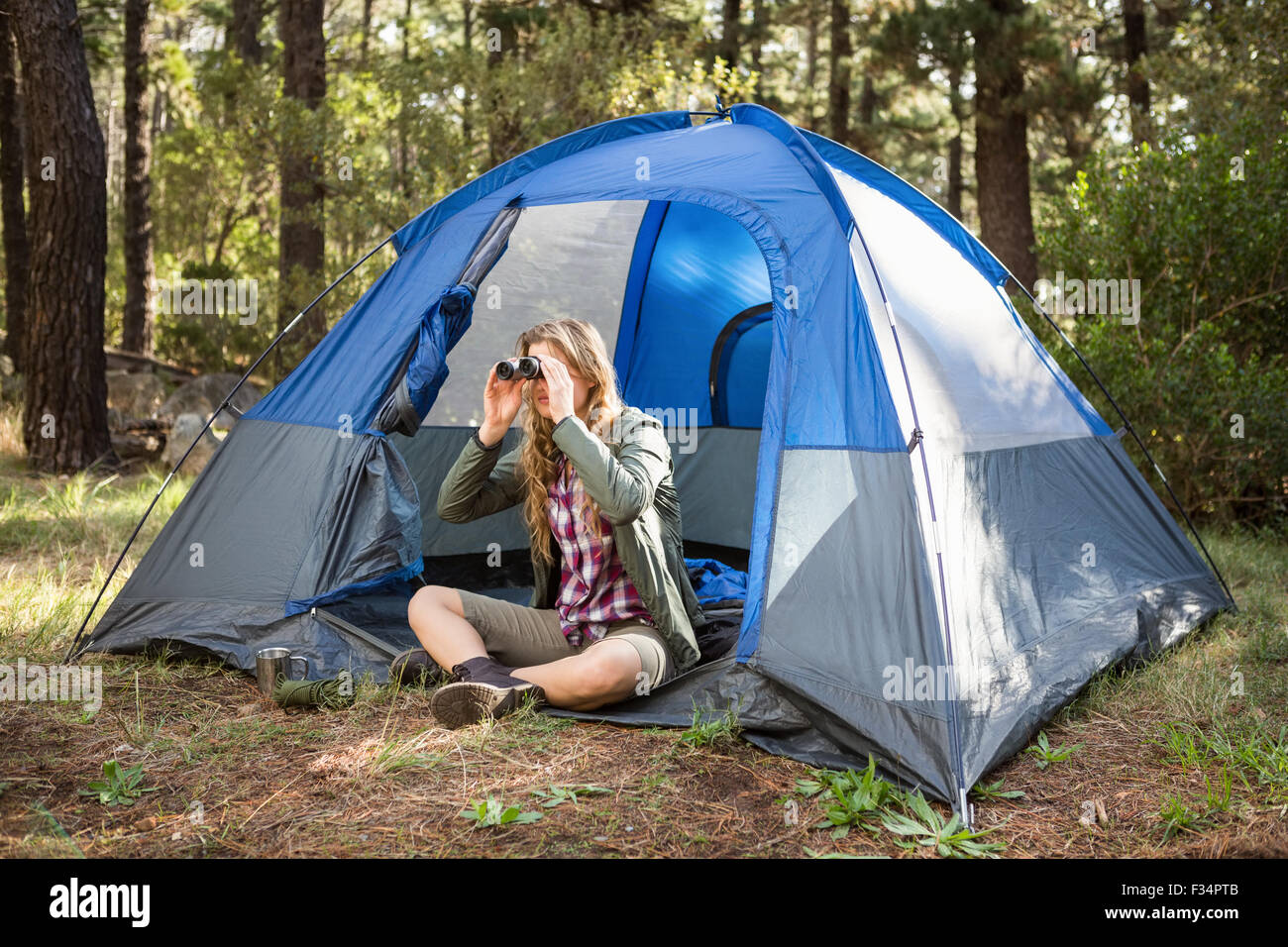 Blonde camper guardando attraverso il binocolo Foto Stock