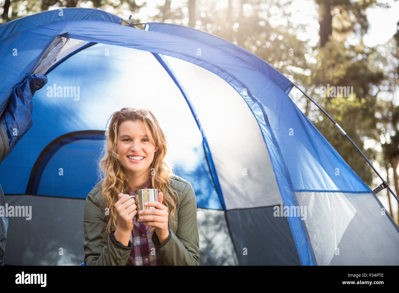 Bella bionda camper sorridente e seduta in tenda Foto Stock