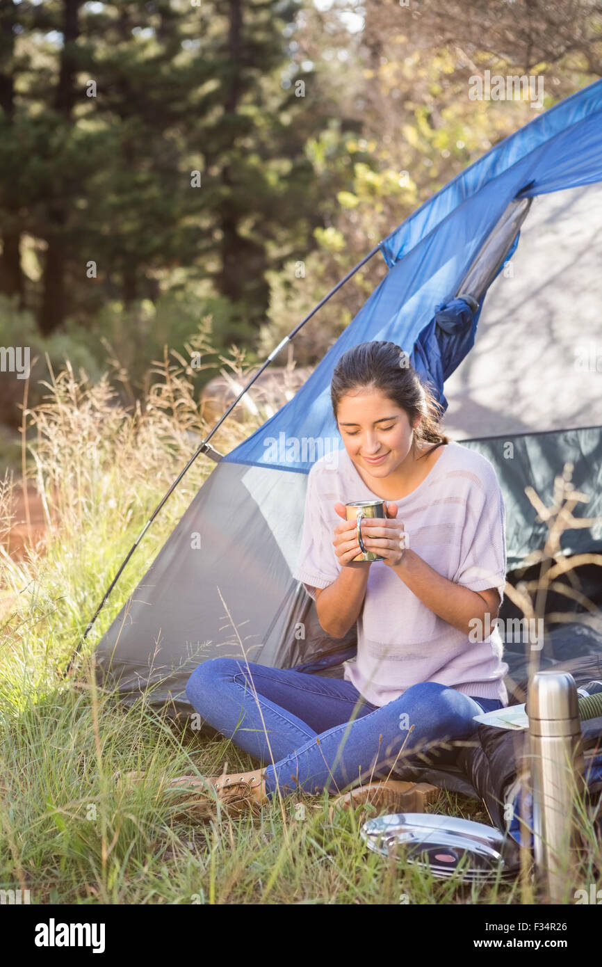 Brunette camper godendo bevande e seduta in tenda Foto Stock