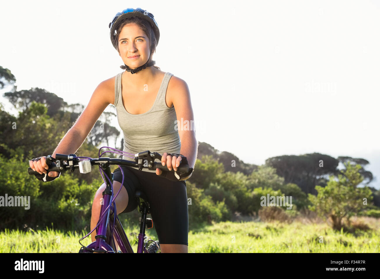 Focalizzato athletic brunette seduta in mountain bike Foto Stock