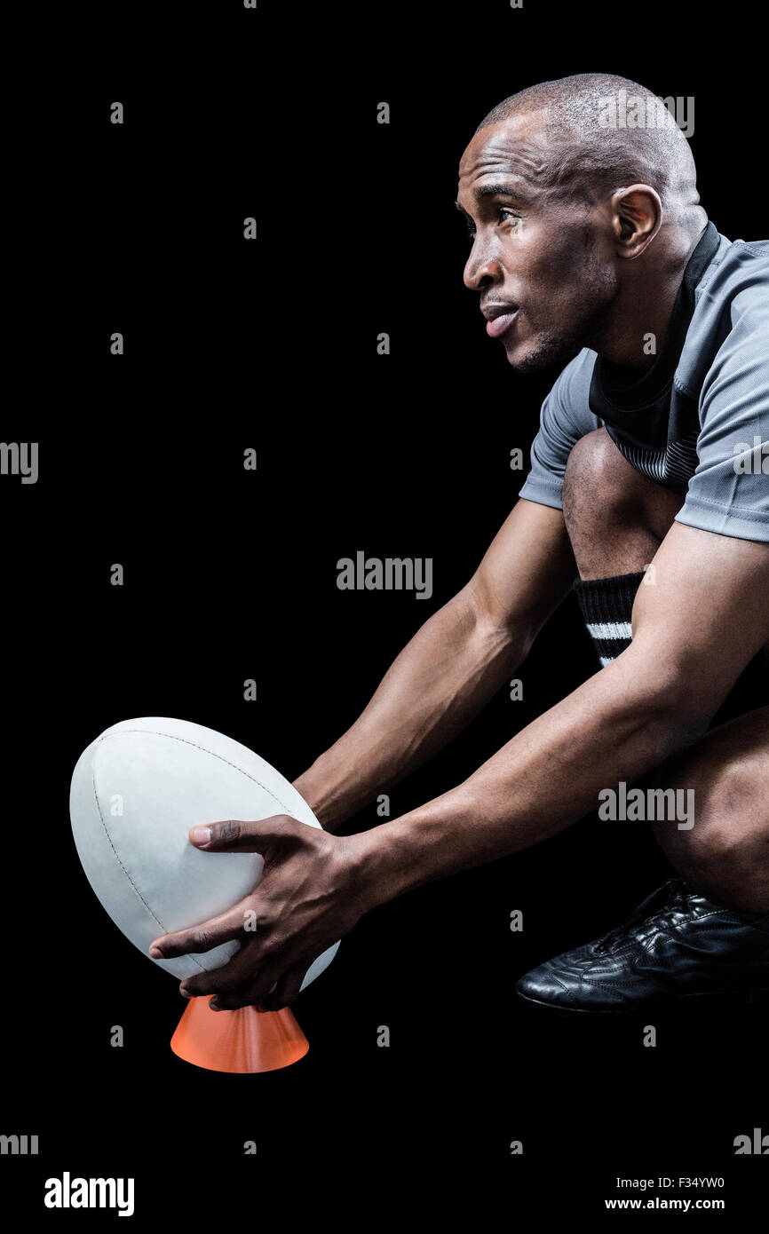 Fiducioso sportivo mantenendo il pallone da rugby sui calci tee Foto Stock