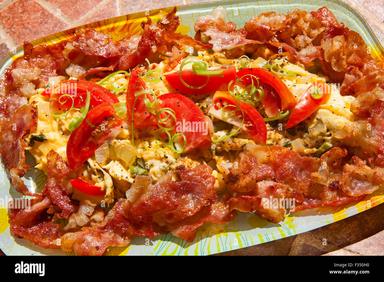 Una colazione frittata di uova con latticini formaggi, verdure - la cipolla, i peperoni, la cipolla verde strisce e cunei di pomodoro. Foto Stock