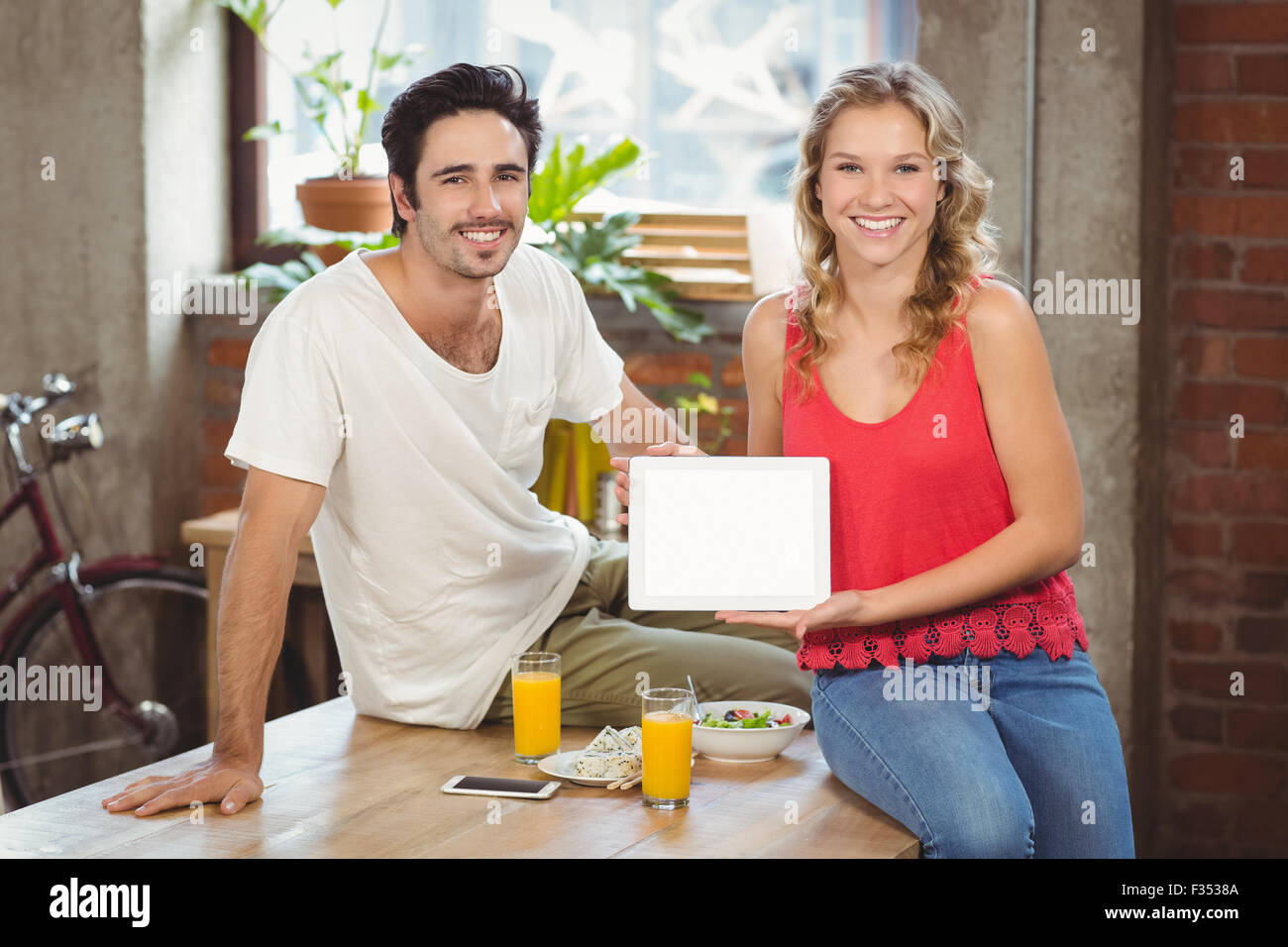 Sorridente la gente di affari che mostra digitale compressa in office Foto Stock