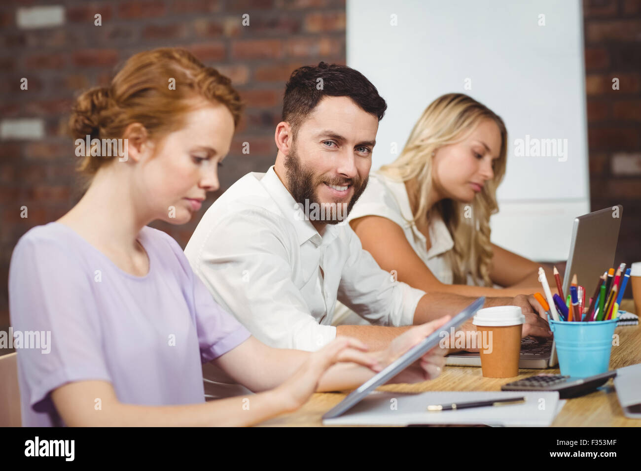 Ritratto di uomo sorridente seduto in mezzo ai colleghi Foto Stock