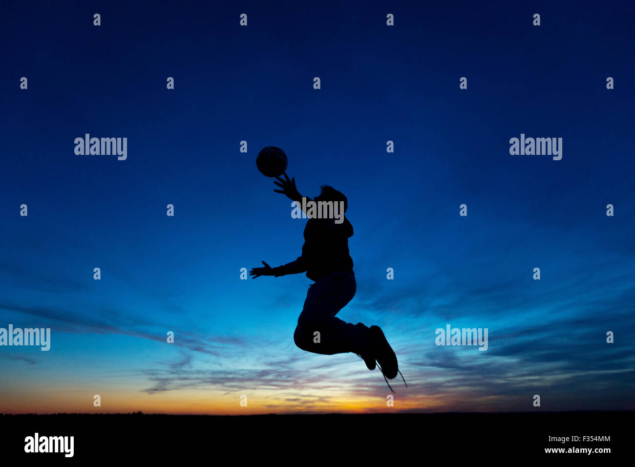Silhouette di un ragazzo giocando fuori al tramonto Foto Stock