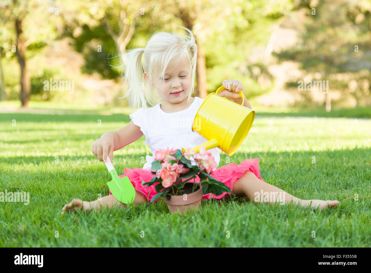 Carino Bambina giocando giardiniere con i suoi strumenti e vaso di fiori. Foto Stock