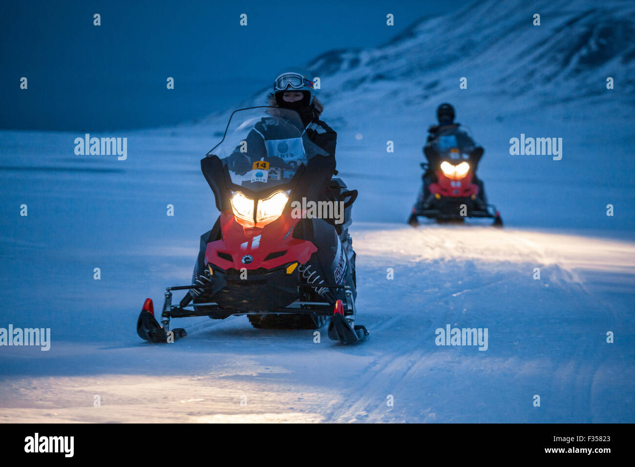 Gli studenti universitari pratica guida motoslitte attraverso Adventdalen, Svalbard come parte della loro formazione di base sulla sicurezza. Foto Stock
