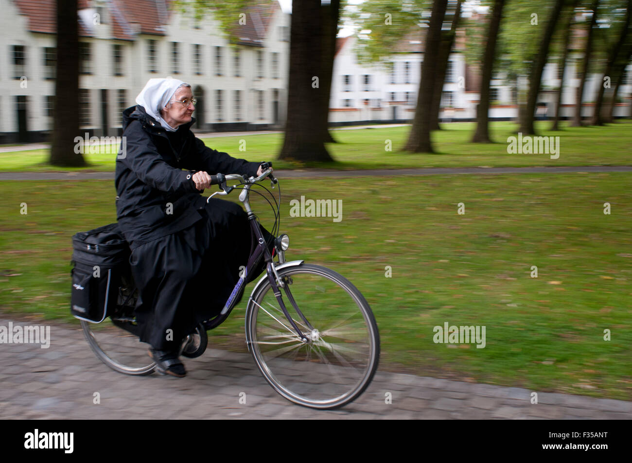 Bruge, monaca un giro in bicicletta. Il beghinaggio di Bruges è stata fondata nel 1245 dalla contessa delle Fiandre, Margaretha di Constantinopel Foto Stock