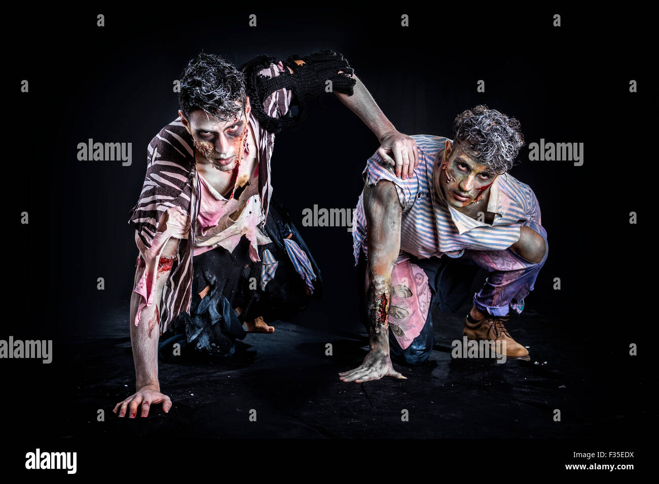 Due maschi zombie strisciando sulle ginocchia, nero su sfondo fumoso, guardando la fotocamera. Tema Halloween Foto Stock
