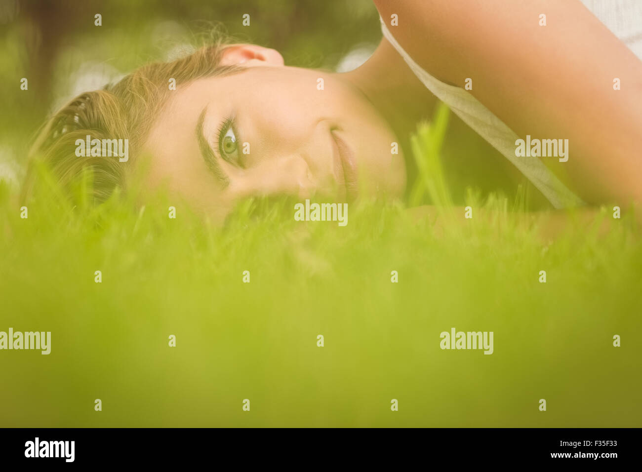 Vista laterale della bella donna sorridente sdraiati sull'erba Foto Stock