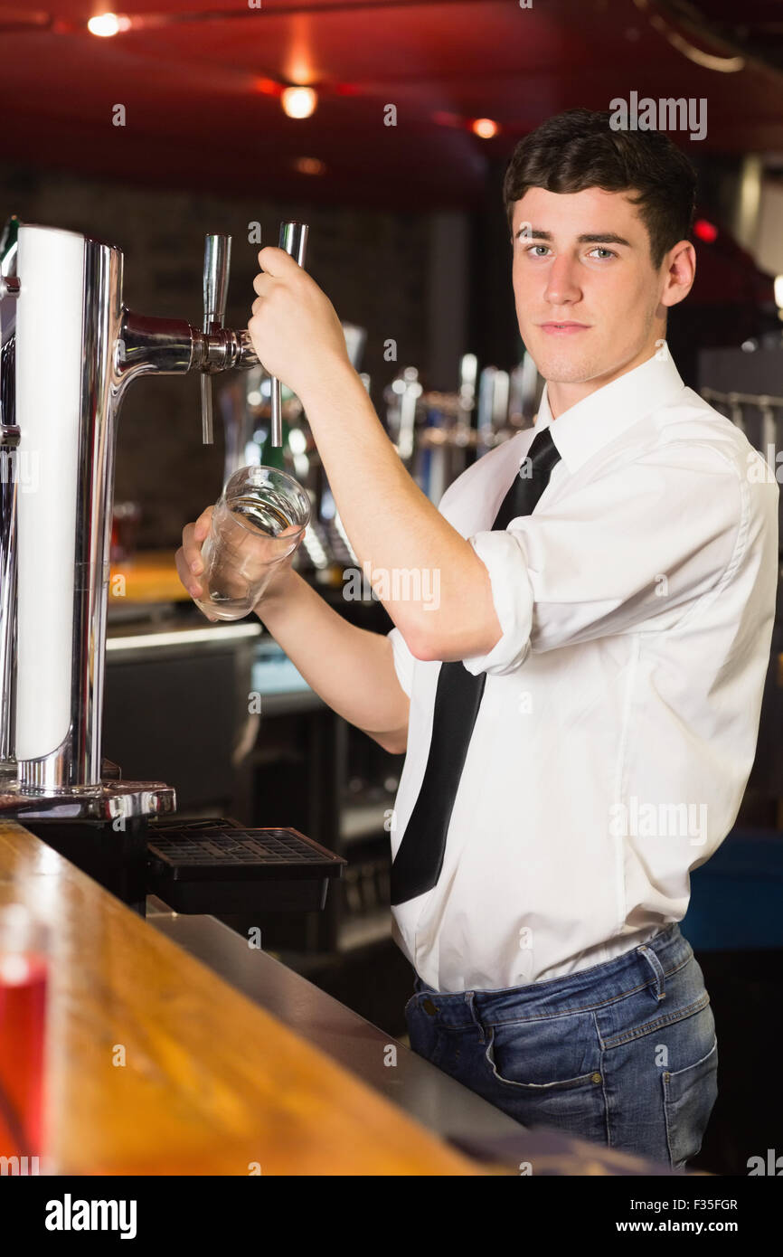 Ritratto di barman holding di vetro al distributore di birra Foto Stock