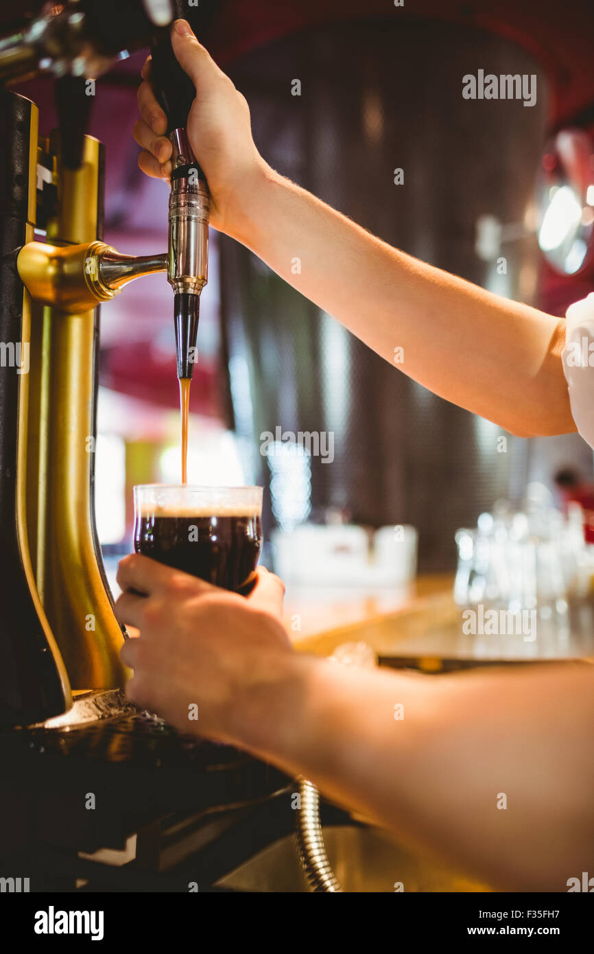 Barista tenendo sotto vetro birra rubinetto erogatore Foto Stock