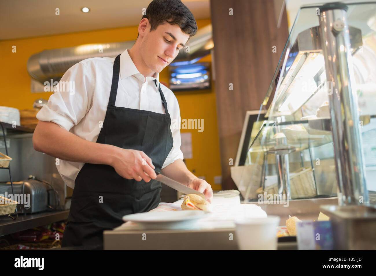 Lavoratore di sesso maschile il taglio di sandwich in vetrina Foto Stock