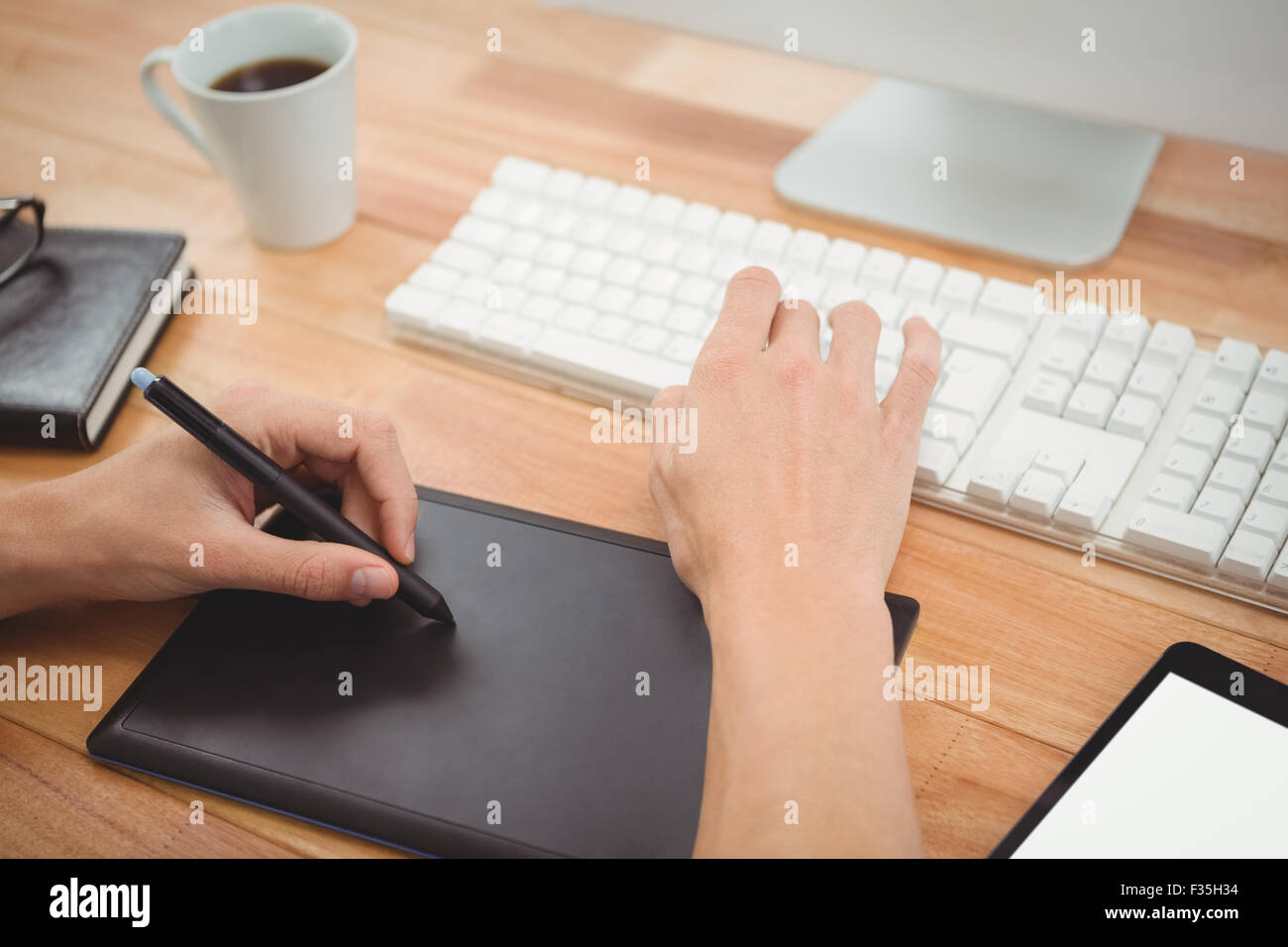 Hipster con tavoletta grafica sulla scrivania in ufficio Foto Stock