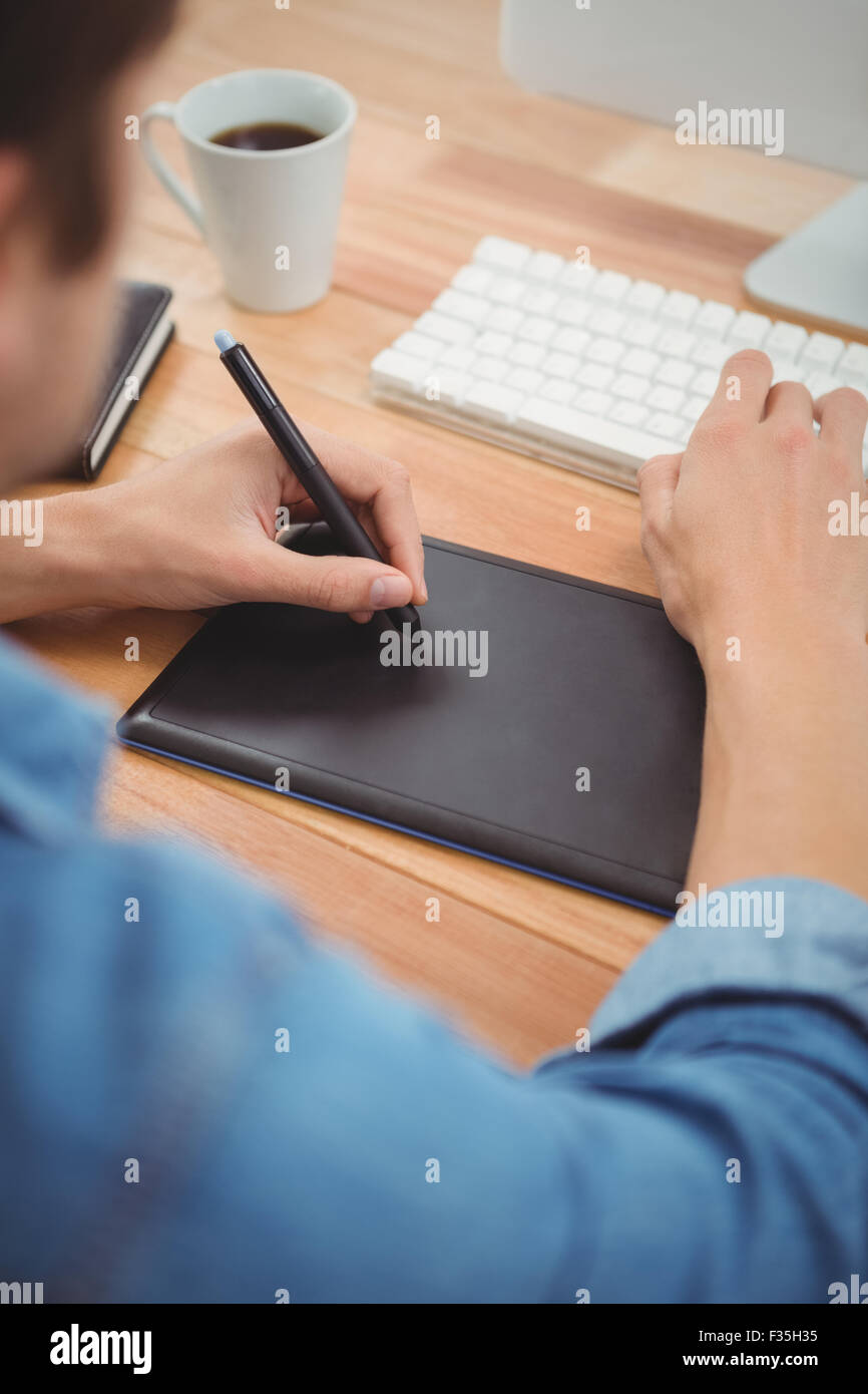 Hipster con tavoletta grafica sul tavolo in ufficio Foto Stock