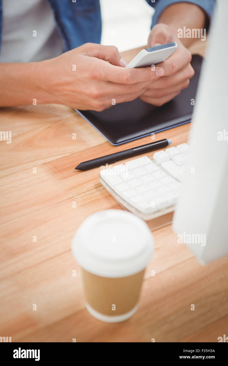 Hipster utilizzando il telefono cellulare alla scrivania in ufficio Foto Stock