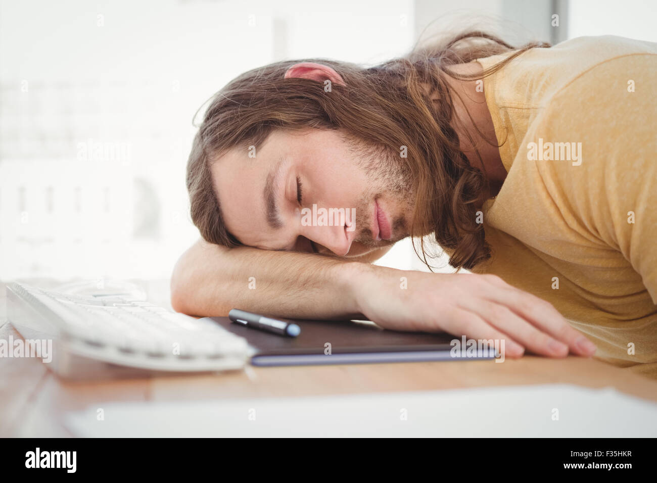 Hipster appoggiato la testa alla scrivania del computer Foto Stock