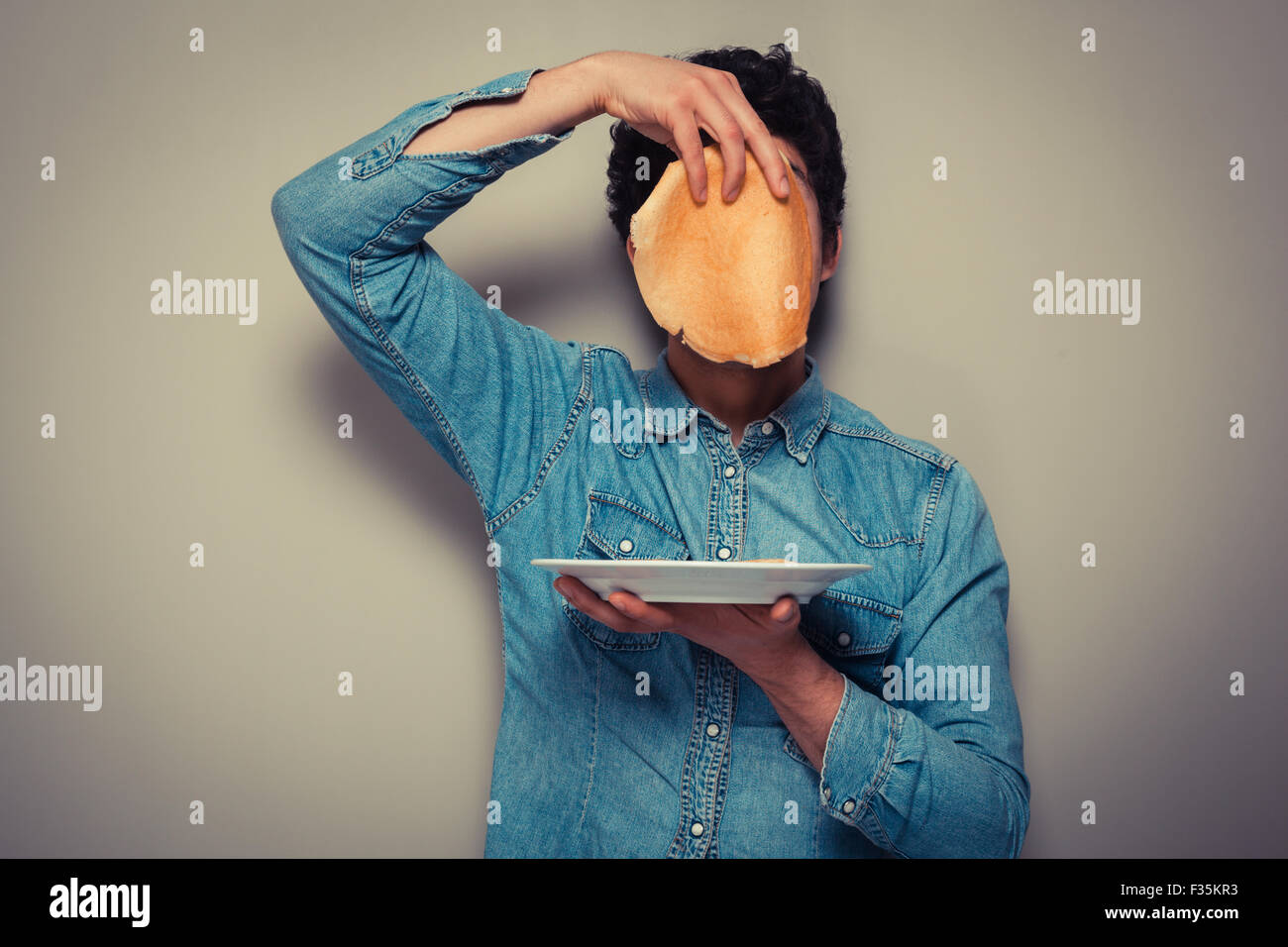 Giovane uomo si nasconde il suo volto dietro un pancake Foto Stock