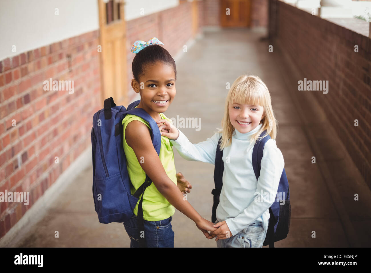 Sorridendo gli alunni tenendo le mani sul corridoio Foto Stock
